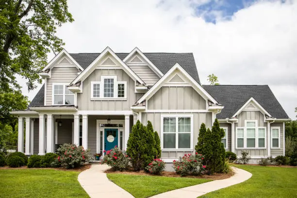 A modern suburban house with a manicured lawn and shrubs.
