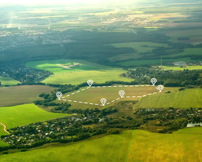 Aerial view of a rural landscape with fields and scattered homes under a cloudy sky.