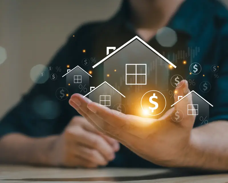 Hand holding a glowing house icon with financial symbols.