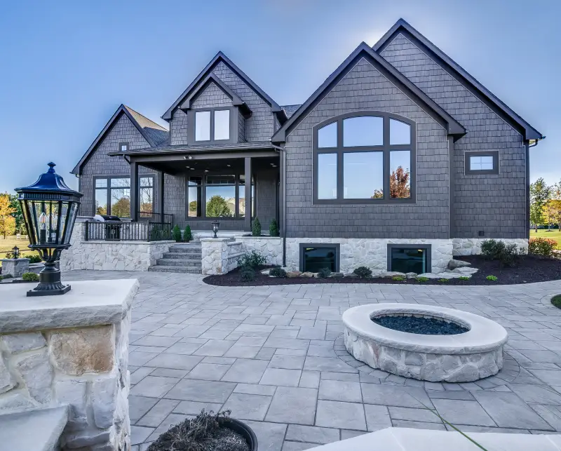 Modern gray brick house with large windows and spacious patio.